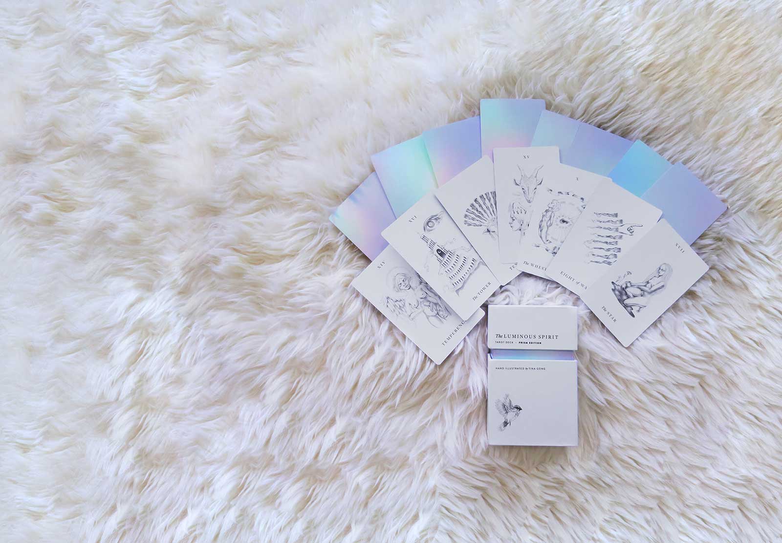 A simple, minimalist tarot deck featuring intricate hand drawn images and simple holographic back.