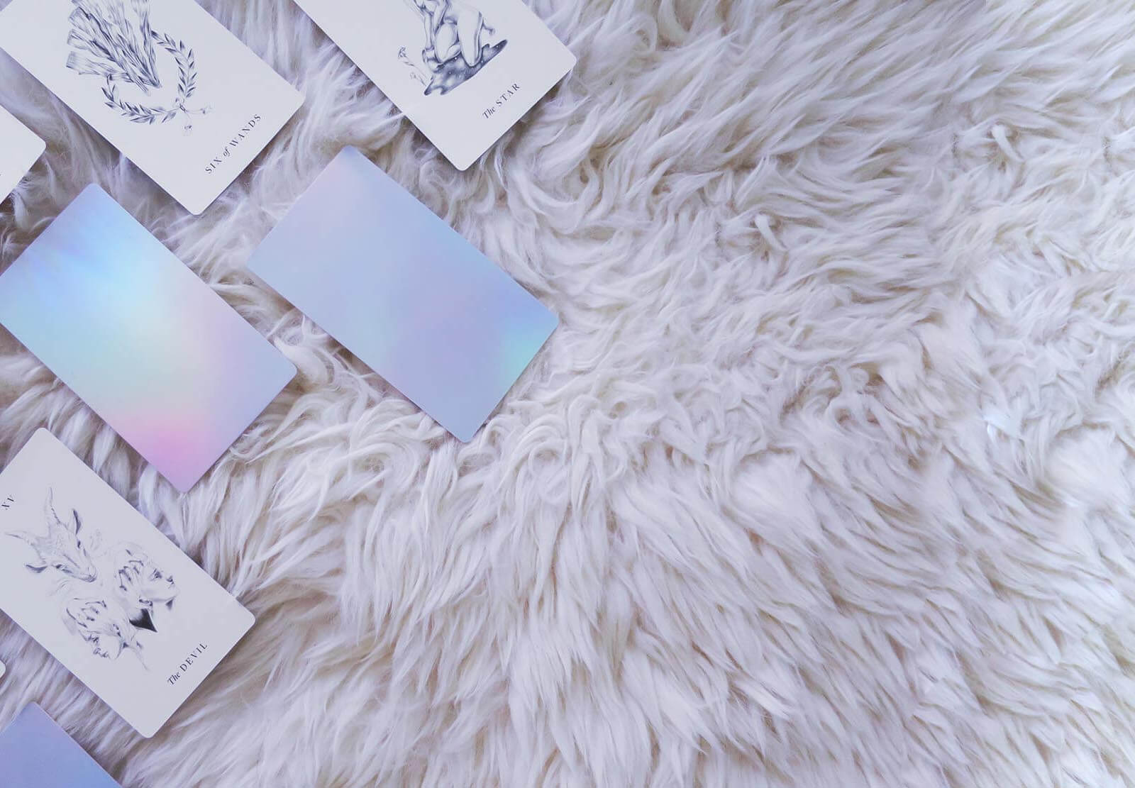 A simple, minimalist tarot deck featuring intricate hand drawn images and simple holographic back.